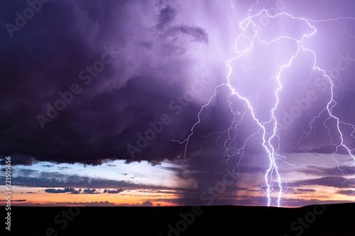 Lightning bolts strike from a sunset storm.