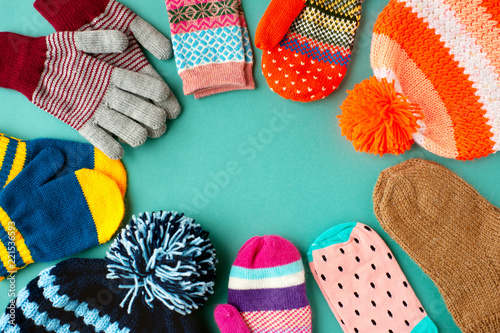 Caps, mittens, gloves and socks are stacked in a circle. View from above. Warm clothes in the form of hats, mittens, gloves and socks for autumn and winter. Warm clothes for cold seasons.
