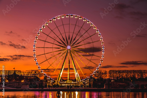 Illuminated ferris wheel with colorful sunset.