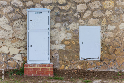 Cajas eléctricas junto a un muro de piedra