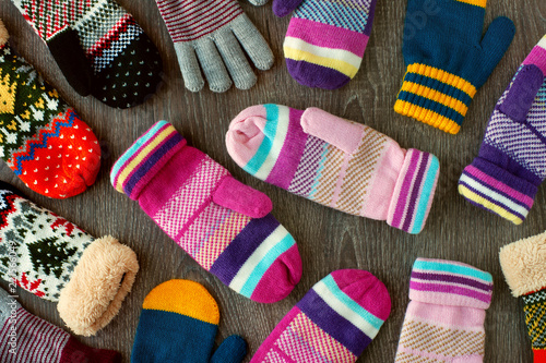 Mittens for winter. View from above. Many multicolored mittens on a wooden background. Warm clothing for hands in the cold season.