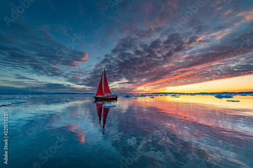 Greenland midnight Sunrise mirror panorama with red sail ship 
