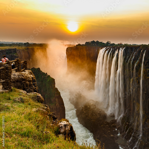 Victoria falls sunset with orange sun and tourists