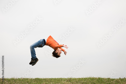 healthy sport little boy jumping somersault outdoors nature with copyspace