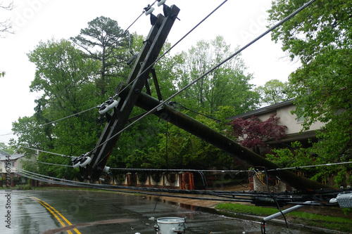 transformer on a pole and a tree laying across power lines over a road after Hurricane moved across