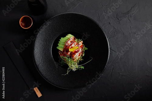 top view of delicious traditional japanese dish with seafood, avocado and herbs on black plate