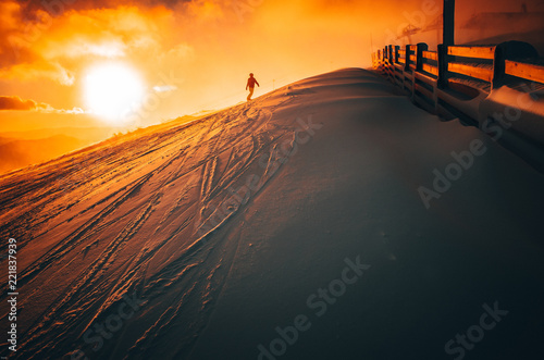 Snowboarder in ski resort. Winter sport photo. Orange sunset light in background. Edit space