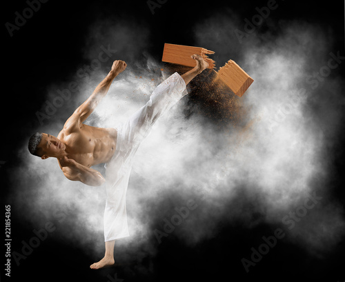 Karate man breaking with leg wooden board
