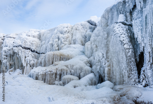 A frozen waterfall with ice in blue and white color in winter. Winter background. Jagala Waterfall, Estonia.