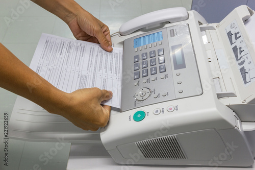 ็Hand man are using a fax machine in the office. Business concept 