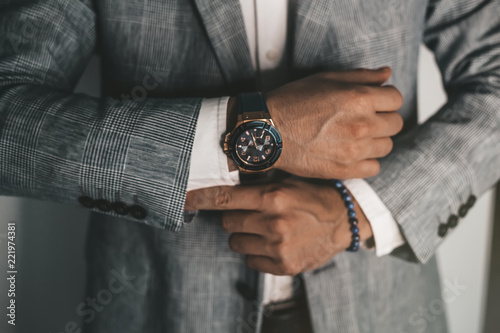 Businessman luxury style. Men style.closeup fashion image of luxury watch on wrist of man.body detail of a business man.Man's hand in a grey shirt with cufflinks in a pants pocket closeup. Toned