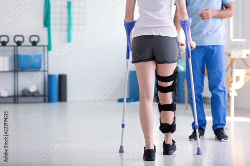 Patient with stiffener on the leg walking with crutches during rehabilitation