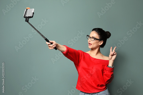 Attractive young woman taking selfie on grey background