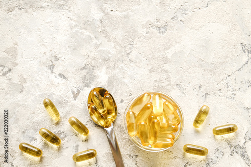 Bunch of omega 3 fish liver oil capsules in silver spoon. Close up of big golden translucent pills in pile. Healthy every day fatty acids nutritional supplement dosage. Top view, flat lay, copy space.