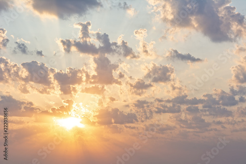 Early morning sky scene with golden sun, clouds and light rays