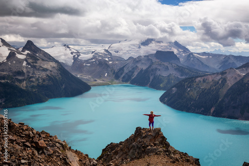 Woman standing on top of the Mountain overlooking a beautiful glacier lake. Taken on Panorama Ridge, Garibaldi, Near Whister, BC, Canada.