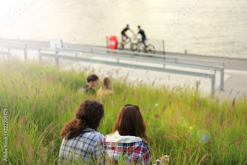 Para młodych ludzi odpoczywa w wysokiej zielonej trawie nad rzeką odrą we Wrocławiu.