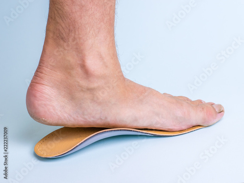 A man tries on an orthopedic insole on the left leg with signs of strong flat feet.