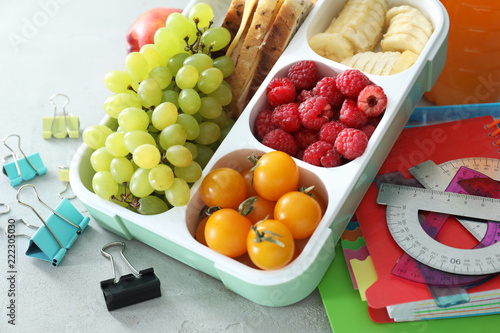 Lunch box with appetizing food and stationery on light table