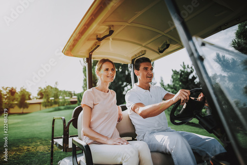 Happy Young Couple in White Cart on Golf Field.