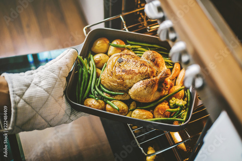 Cook taking ready chicken from the oven