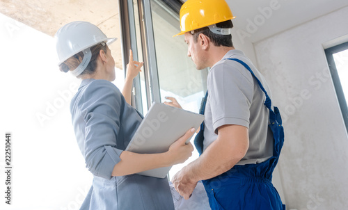 Architekt und Arbeiter auf Baustelle überprüfen die Fenster im Rohbau