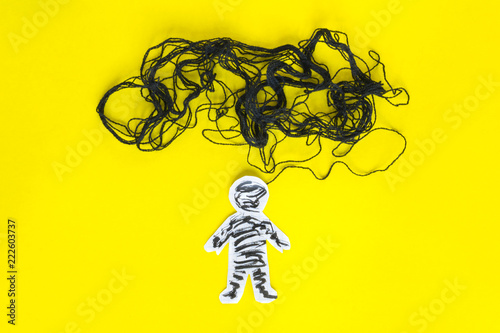 Negative thinking concept, paper man and black thread on the yellow background.