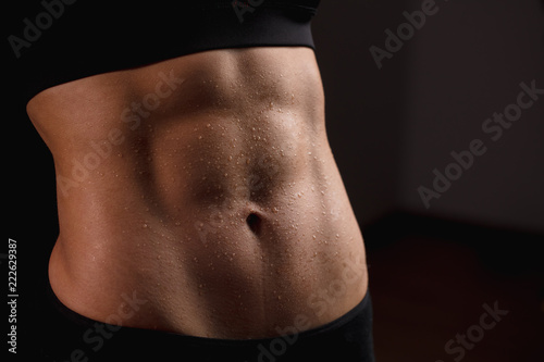 Close up of fit female abs isolated on black background with copy space. Fitness female and trained stomach, Perfect Slim Body. Sport, Bodybuilding, Fitness Concept