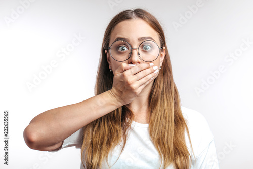 Young surprised Caucasian woman closing her mouth with hand on white background. girl cannot keep secrets. cute woman spills the beans
