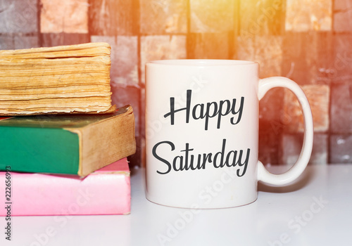 Happy saturday word on white morning coffee cup and books