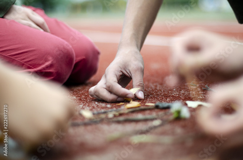 Dłonie dzieci układające napis z patyków i liści jesiennych