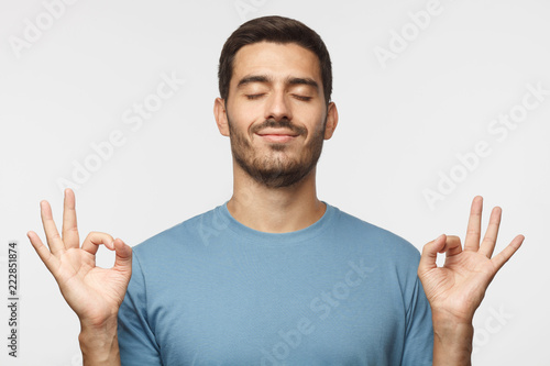 Happy smiling man standing with closed eyes, having relaxation while meditating, trying to find balance and harmony isolated. Yoga and meditation. .