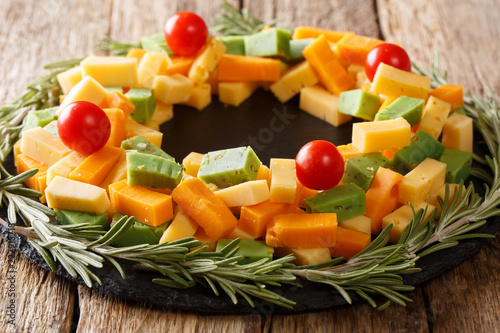 delicious Christmas set of pesto cheese, cheddar, mimolette with tomatoes and rosemary close-up on the table. horizontal