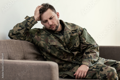 Unhappy and sad soldier in green moro uniform with war syndrome