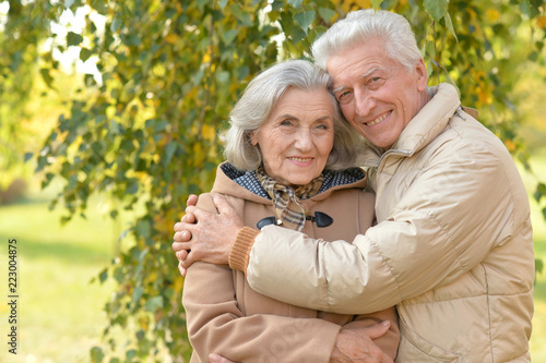 Happy senior couple in autumn park hugging 