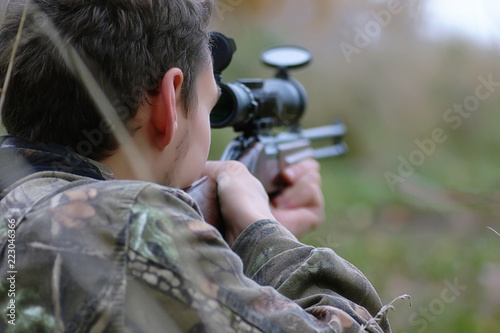 Man in camouflage and with guns in a forest belt on a spring hun