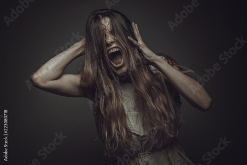 Crazy, deranged young woman screaming with frustration, expressing madness and rage