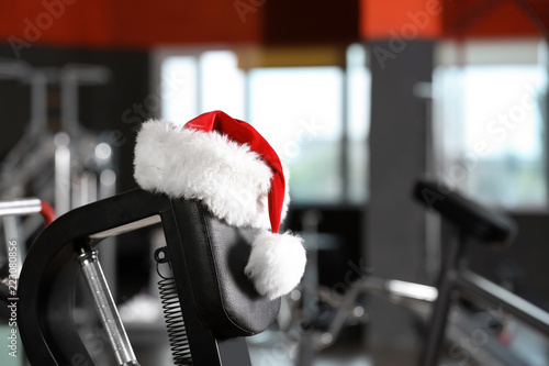 Santa Claus hat on modern exercise machine in gym