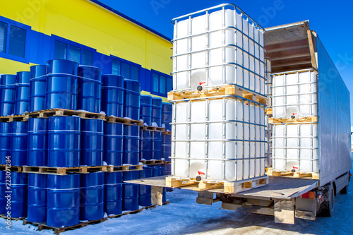 Discharge of plastic barrels. Barrels for the chemical industry. Blue metal barrels. White plastic containers. Chemical industry. The machine brought chemical substances.