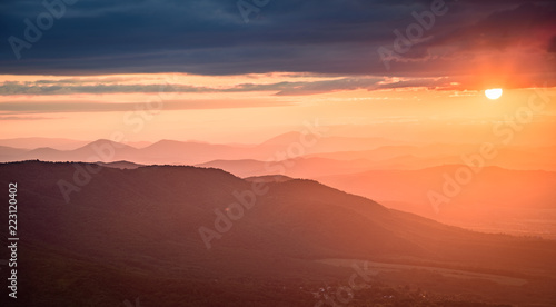 Amazing sunset in the mountains - beautiful golden light peaking through storm clouds with vivid colors and picturesque scenery - perfect relaxation spot