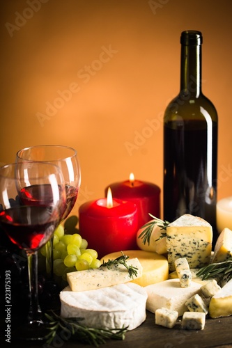 Wine Bottle, Wine Glasses, Lit Candles, Cheeses and Grape on