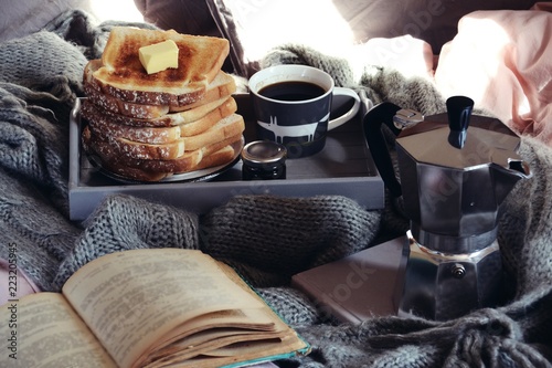 Cozy home with cup of coffee with blanket and book. Hygge home interior. Hygge style breakfast in bed 