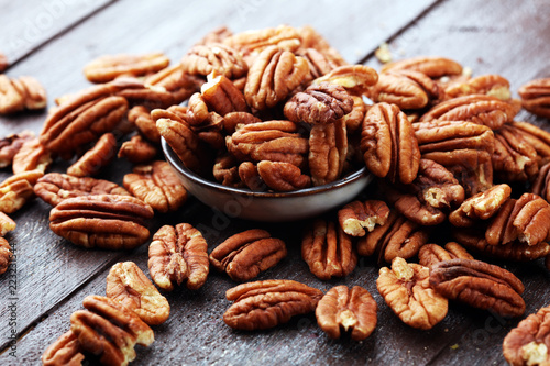Pecan nuts on a rustic wooden table and pecan nuts in bowl
