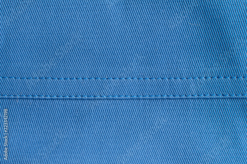 Stitches on blue fabric .