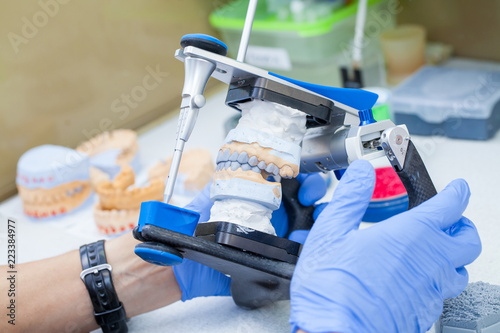 Dental technician working with articulator in dental lab