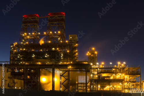 Night industrial landscape with bright lights of lanterns - 4-drum delayed coking unit in a petroleum refinery
