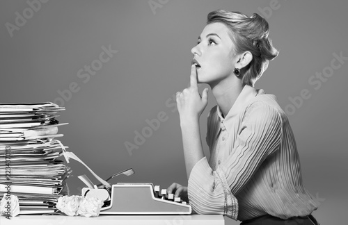 Young blonde female writer using typing machine