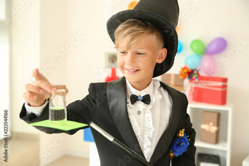 Cute little magician showing trick indoors