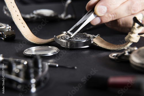 Detail of the work of a watchmaker who replaces a battery / Close up of replacing a watch battery with watchmaker tools