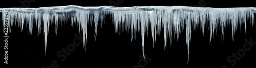 Icicles on an black background, isolated object. Panoramic photo.
